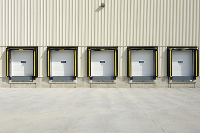 Warehouse Loading Dock with 5 white garage doors and other loading dock equipment surrounding them