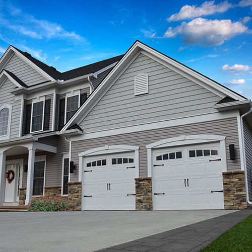 a home with an attached garage that features 2 white garage doors